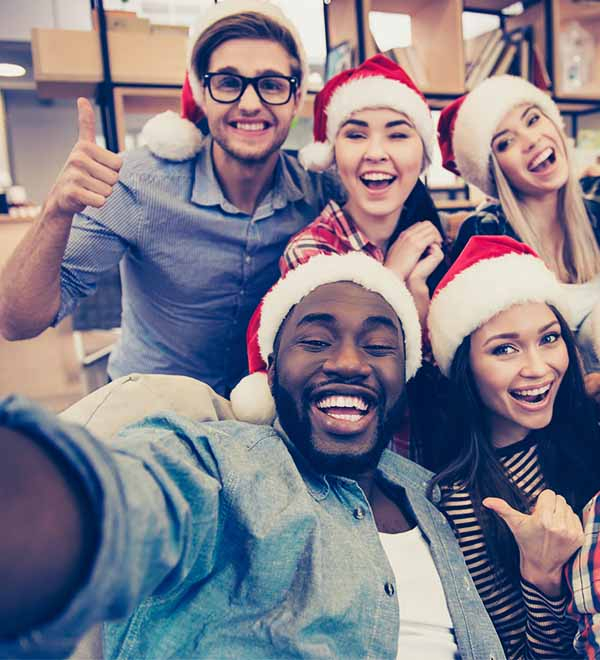 Vijf collega’s dragen een kerstmuts en nemen een vrolijke selfie