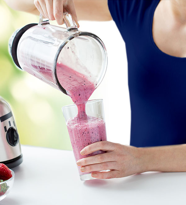 Woman pouring pink smoothie into glass
