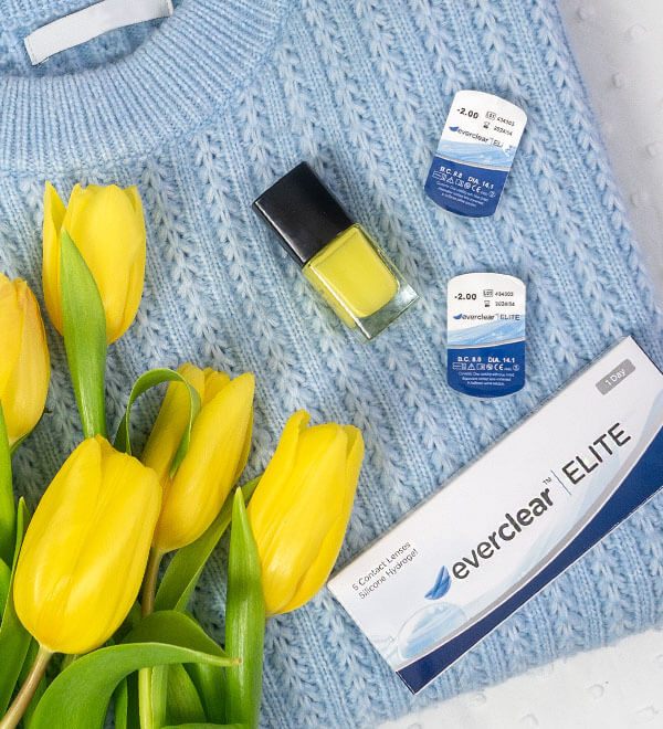 Caja de muestra de las lentillas everclear ELITE, tulipanes y pintauñas amarillo sobre un jersey azul