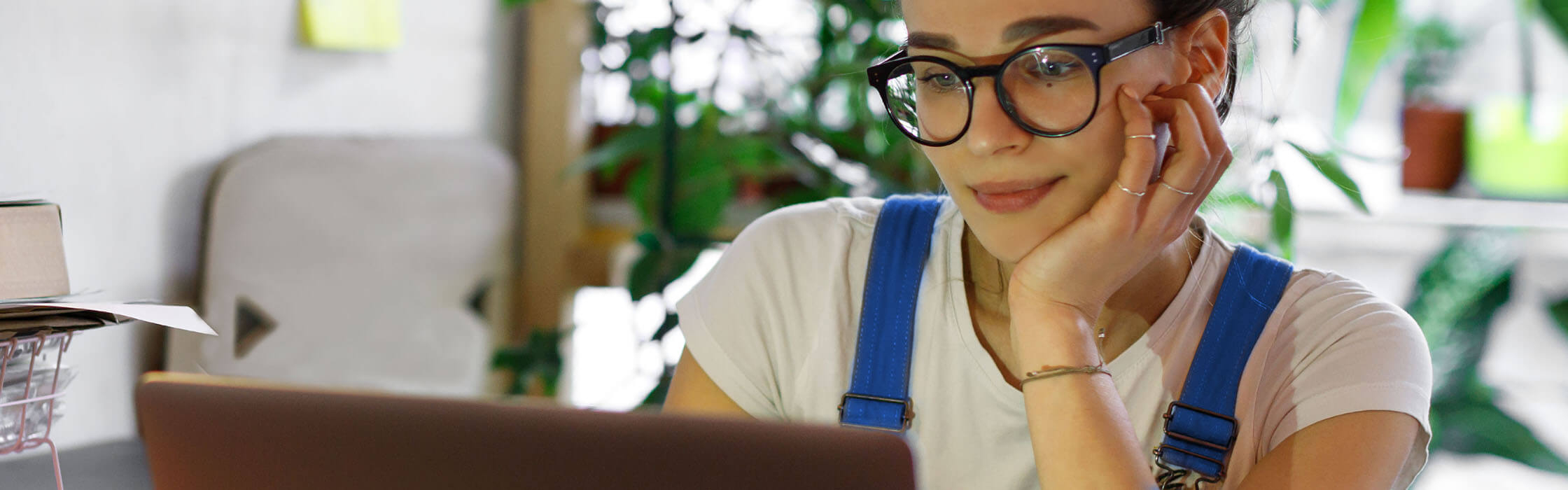 A woman wearing glasses looking at a laptop