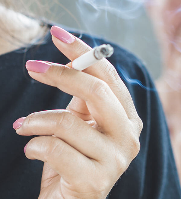 Main d’une femme fumant une cigarette