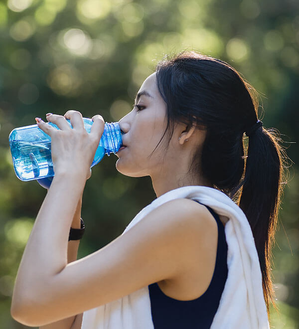 Een vrouw in een sportieve outfit drinkt een flesje water