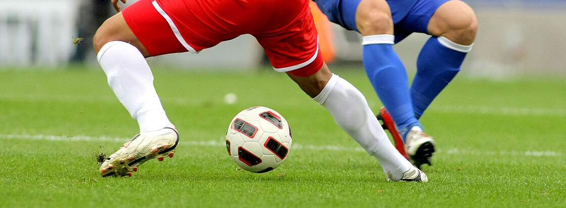 De benen van twee voetbalspelers op het veld en een bal