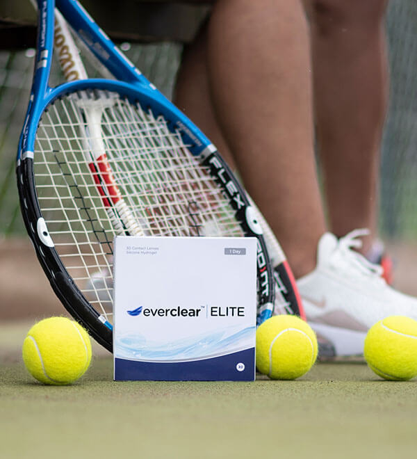 Een doosje everclear ELITE lenzen met op de achtergrond een tennisracket en tennisballen