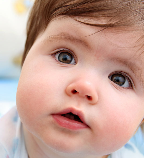 Een lachende baby met blauwe ogen

