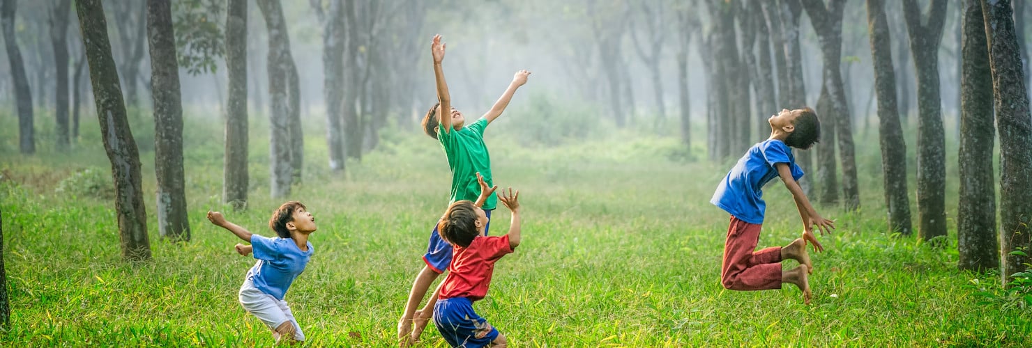 Vier kinderen springen in het gras
