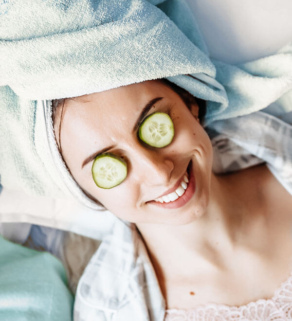 Een vrouw is aan het ontspannen met twee plakjes komkommer op haar ogen
