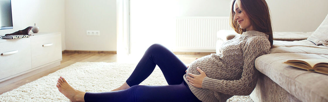 Zwangere vrouw zit op de vloer in de woonkamer