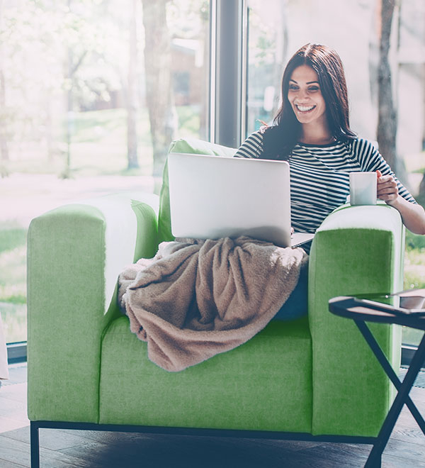 Femme assise avec son café et son ordinateur portable sur ses genoux