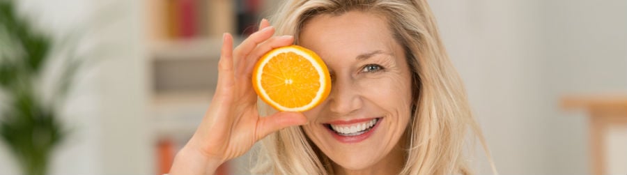 Femme tenant une tranche d’orange devant son œil