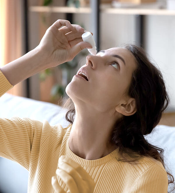 A woman applying eye drops