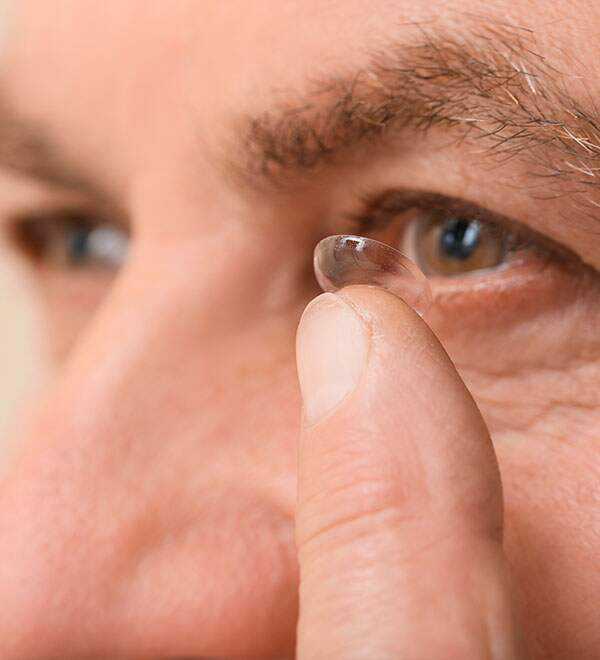 Een man met bruine ogen doet een contactlens in