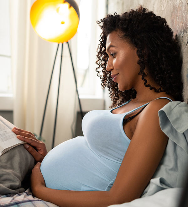 Femme enceinte lisant un livre dans son lit