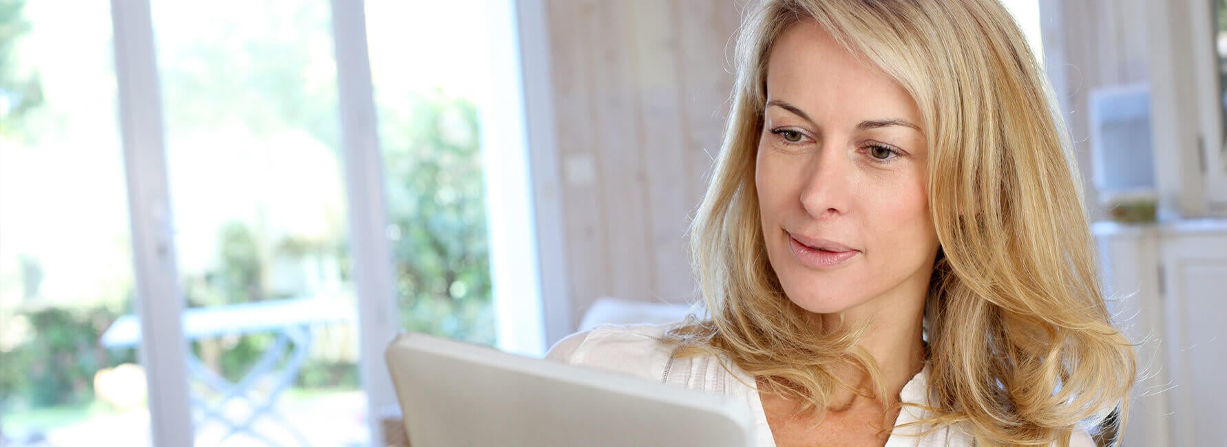 Een vrouw met blond haar leest op een tablet